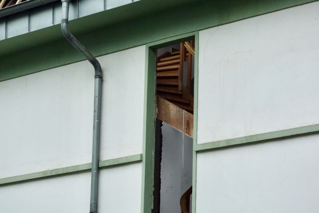 Storm-damaged house with a broken roof and exposed timbers after high winds